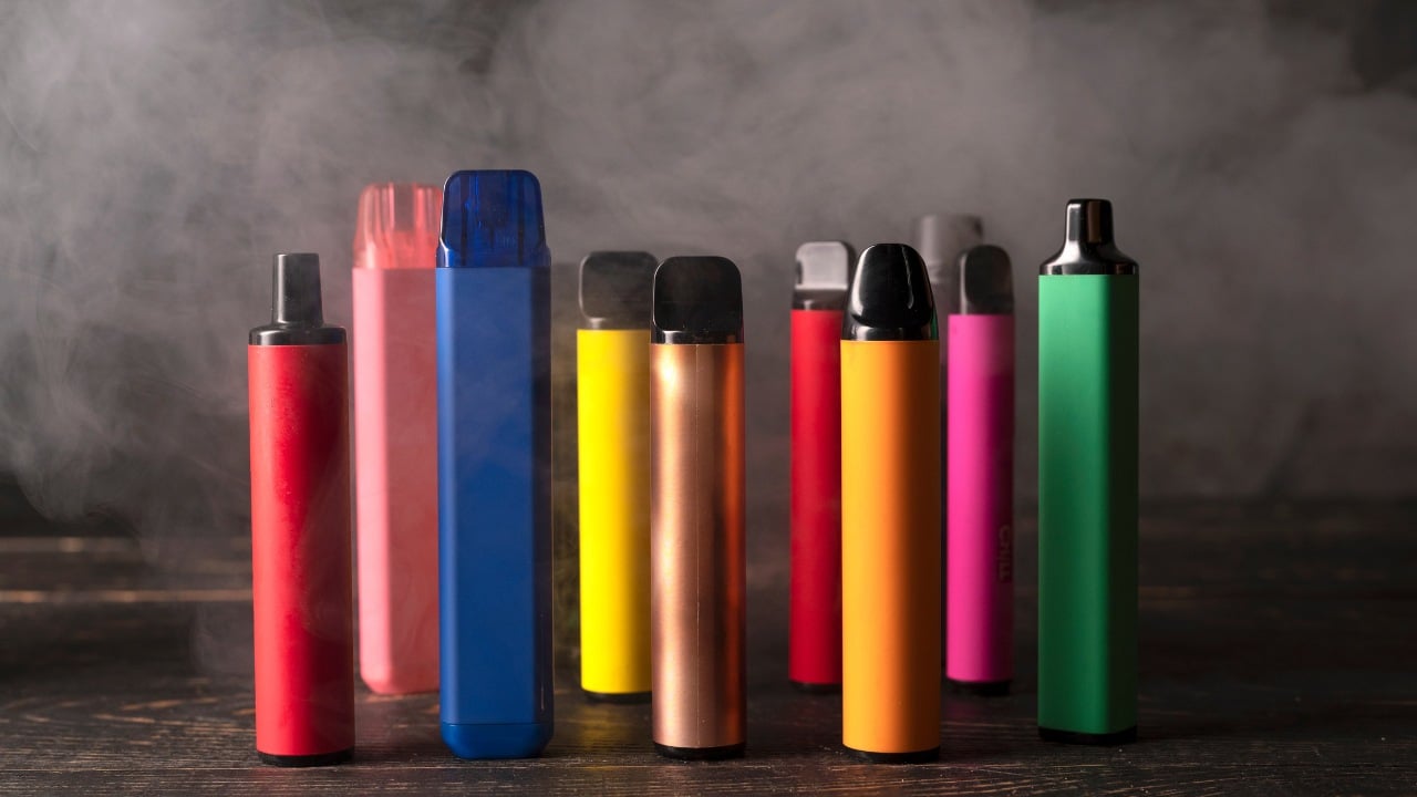 A person holding a disposable vape against the sky, symbolizing sourcing and logistics